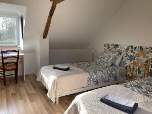 a bedroom with two beds and a desk and a window at La suite de L'Eau qui dort in Pleslin-Trigavou
