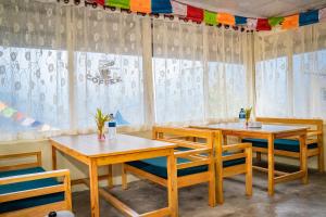 a restaurant with wooden tables and chairs and curtains at Chautari Hotel & Restaurant in Astam
