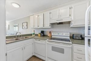 a kitchen with white cabinets and white appliances at Coastal 2BR Condo w Ocean Views & Pool in Hilton Head Island