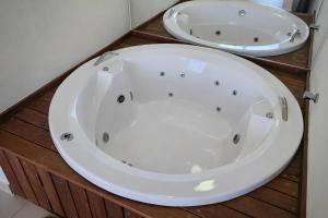 a white bath tub in a bathroom with two sinks at Chalés Brisas do Lago Capitólio in Capitólio