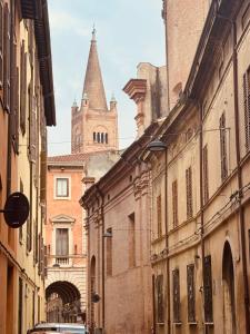 an alley between two buildings with a cathedral in the background at Novecento Apartment in Forlì