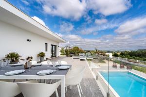 a patio with a table and chairs and a swimming pool at Villa Adão Lobo in Cadaval