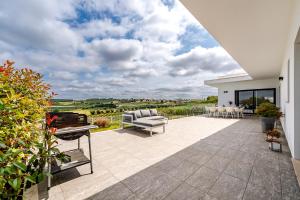 a patio with chairs and a grill on a house at Villa Adão Lobo in Cadaval