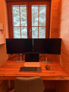 a desk with a computer monitor and a laptop on it at Chalet Spatz Loft with Sauna Kandersteg Oeschinen Lake in Kandersteg
