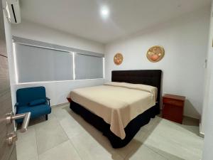a bedroom with a bed and a blue chair at Fantástico Depa en BLUU con Playa Artificial ! in Mazatlán +37 photos
