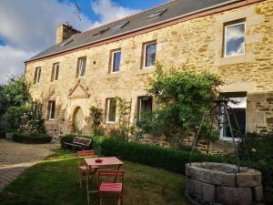 a stone house with a table and chairs in front of it at LE DOMAINE DE COAT ROGAN, La chambre du Jaudy in Pommerit-Jaudy