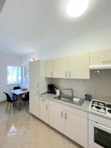 a kitchen with white cabinets and a dining table at Apartman & rooms Draga in Marina