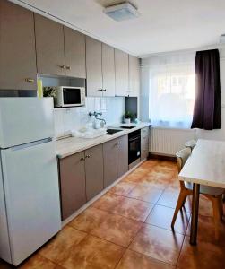 a kitchen with a white refrigerator and a table at Indira Vendégház in Nyíregyháza
