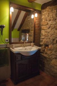 ein Bad mit einem Waschbecken und einem Spiegel in der Unterkunft El Mijolar Apartamentos in Armaño