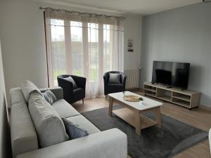 a living room with a couch and a tv at Escapade in Soulaines-Dhuys
