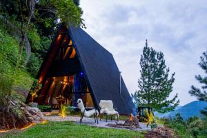 a black triangular house with two white chairs in front of it at Retiro Empíreo in Nova Petrópolis