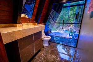 a bathroom with a toilet and a sink and a window at Retiro Empíreo in Nova Petrópolis +40 photos