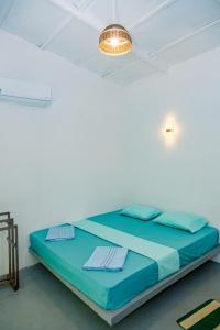 a bed in a white room with a light at Lazy Monkey Green Chalets in Hiriketiya