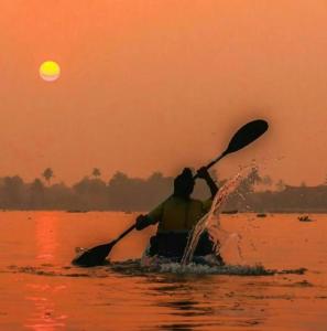 a man paddling a canoe in the water at sunset at Paradise beach homestay in Alleppey