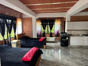 a room with two beds and a kitchen with windows at Hotel Montañitas in Guatapé