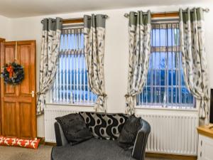 a living room with a couch and two windows at Stonebank Cottage - Uk35686 in Hunwick