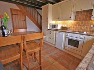 a kitchen with a table and chairs and a microwave at Granary Cottage Whittingham in Whittingham