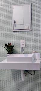 a white bathroom sink with a mirror on a wall at Apto no coração de Serra Negra in Serra Negra +17 photos