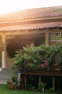 a house with a porch with a bush of flowers at POUSADA ACONCHEGO MT in Chapada dos Guimarães