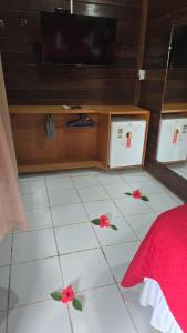a bedroom with a television and a white floor with flowers at Pousada Capim Açu in Fernando de Noronha
