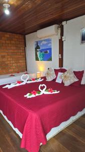 a bed with a red bedspread with two olympics on it at Pousada Capim Açu in Fernando de Noronha