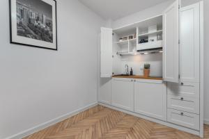 a kitchen with white cabinets and a wooden floor at AURA 77 Żoliborz in Warsaw