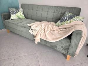 a grey couch with a blanket on top of it at La suite a pochi passi dal mare in Trapani