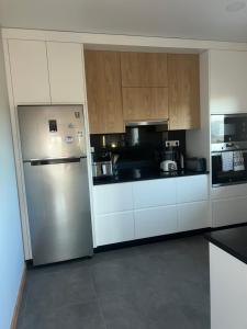 a kitchen with white cabinets and a stainless steel refrigerator at Casa das hortensias in Tabaçô