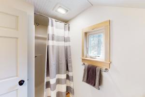 a bathroom with a shower curtain and a window at Half-Mile to Crystal Lake! Couples Retreat w/ Deck in Beulah +20 photos