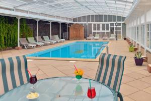 a pool with a glass table and chairs next to a pool at Contact Hotel Le Moulin Neuf Chantonnay in Chantonnay