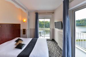 a hotel room with a large bed and a balcony at Contact Hotel Le Moulin Neuf Chantonnay in Chantonnay