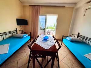 a room with two beds and a table and a window at Sea View in Dhermi in Gjilek