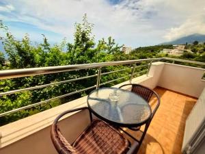 a balcony with a glass table and chairs on a balcony at Sea View in Dhermi in Gjilek