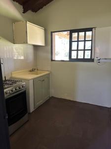 a kitchen with a stove and a sink and a window at Las Dalias in Tacuarembó