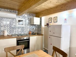 a small kitchen with a refrigerator and a table at Perla 19 - UN LETTO IDEALE in Gaeta +11 photos