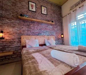 two beds in a room with a brick wall at Saish Stay in Ruhengeri
