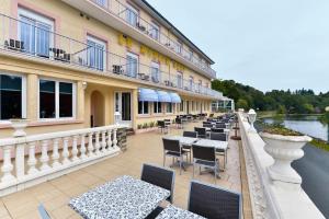 a row of tables and chairs on the balcony of a hotel at Contact Hotel Le Moulin Neuf Chantonnay in Chantonnay