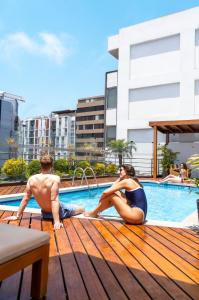 a man and a woman sitting next to a swimming pool at Jose Antonio Executive in Lima
