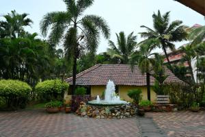 a fountain in front of a building with palm trees at Scandi-Stay 2BR by Benaulim Beach in Benaulim