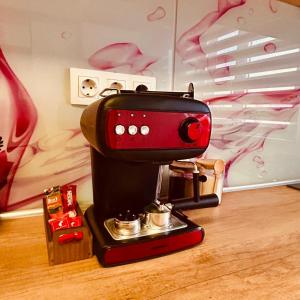 a red and black coffee maker sitting on a table at Sweet Home Apartment in Piteşti
