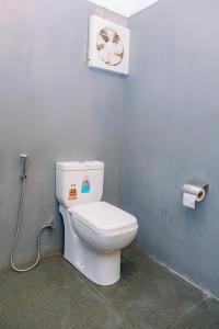 a bathroom with a white toilet in a room at Lazy Monkey Green Chalets in Hiriketiya