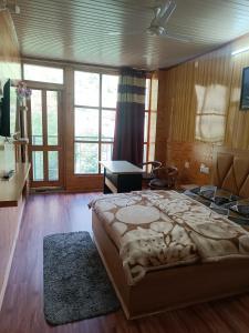 a bedroom with a large bed and a desk at Apple Bud Homestay in Ghund