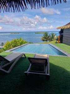 a swimming pool with two lounge chairs and the ocean at Faré Mahi Mahi in Uturoa