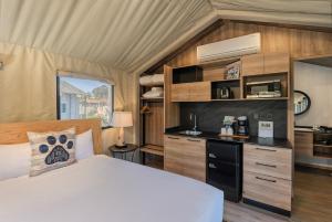 a bedroom with a bed and a kitchen in a tent at Carmel River Inn & Cottages in Carmel