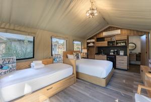 a bedroom with two beds and a kitchen at Carmel River Inn & Cottages in Carmel