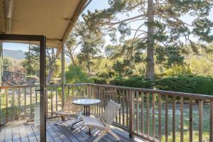 a porch with two chairs and a table on a deck at Carmel River Inn & Cottages in Carmel