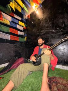 a man sitting on the ground playing a guitar at Cozy Inn Hostel in New Delhi