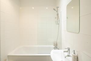 a white bathroom with a tub and a sink at Huge Modern 3 Bed Flat Central For Sightseeing in London +46 photos