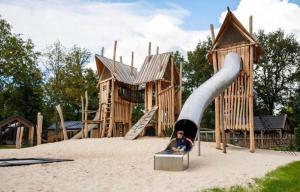 a child sitting in front of a slide in a playground at Vakantiehuisje op 5 star kindercamping in Mariënberg