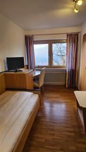 a room with a bed and a desk with a computer at Huberwirt am Kellerberg in Wasserburg am Inn